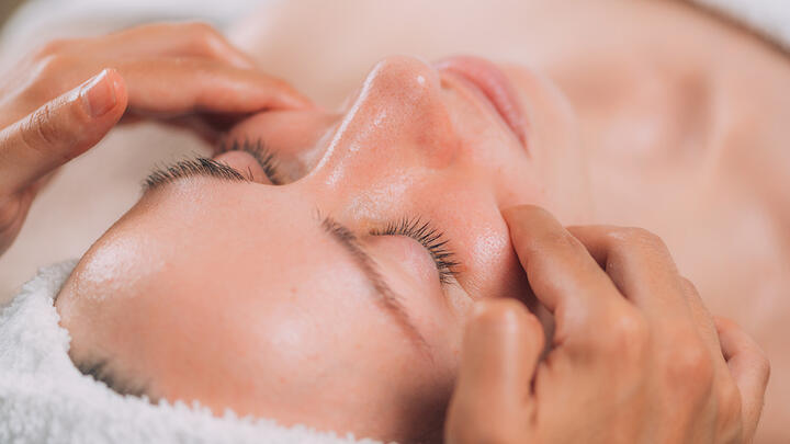Hands performing a massage on women's face